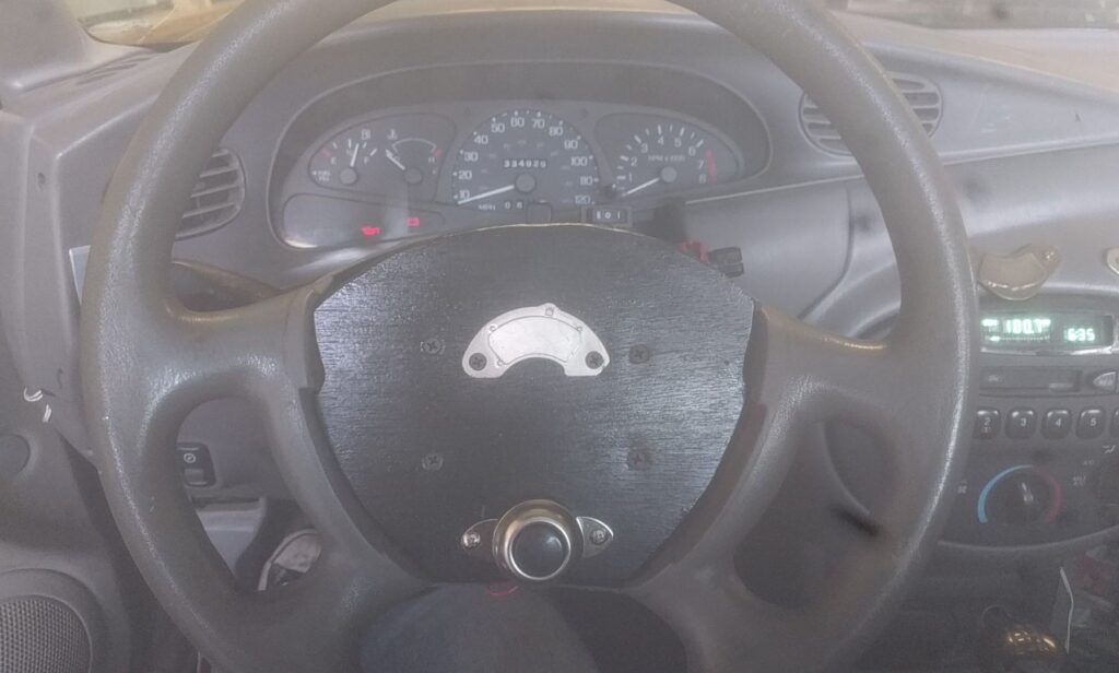 Magnet and aftermarket horn on steering wheel.